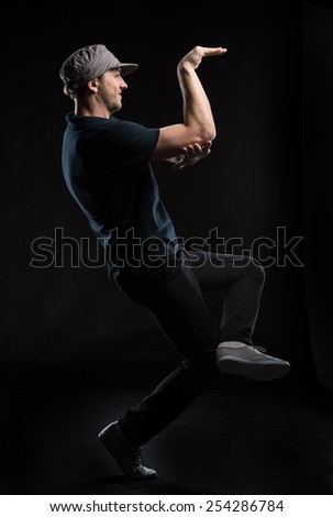 young dancer isolated on black background in studio. Young man dancing in dark studio with hat