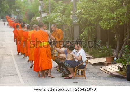 Lao People\'s Democratic Republic, Luang Prabang - 20 JUNE: People giving alms to buddhist monks on the street, Luang Prabang, 20 JUNE 2014.