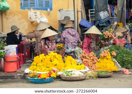 Hoi An, Vietnam - March 14: Vietnamese women in conical hat selling flowers at the street market on March 14, 2014 in Hoi An, Vietnam.