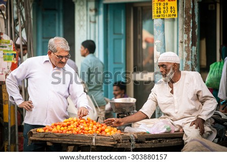 Delhi, India - September 18, 2014: Indian man buying tomatoes from muslim vendor on the street of Old Delhi, India on September 18, 2014.