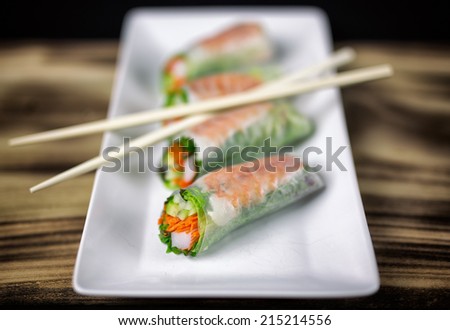 Summer roll sushi on a white rectangular plate with chopsticks.