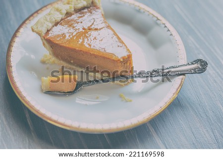 Pumpkin pie on a white china plate with gold detailed rim and antique silver dessert fork.