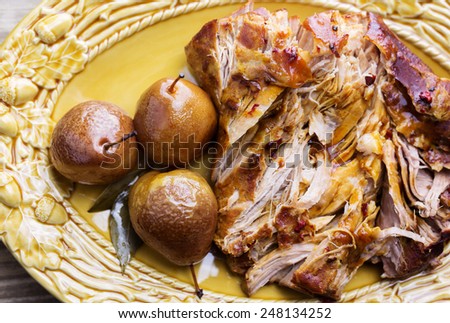 Shredded roast pork on a yellow serving platter with three pears and bay leaves.