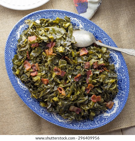 Southern style collard greens with bacon served on an antique plate with burlap table runner.
