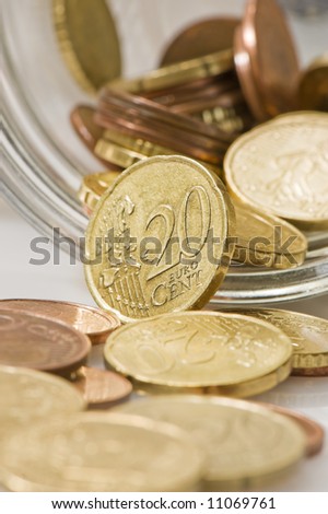 euro cents rolling out of pot. Focus on twenty cents.