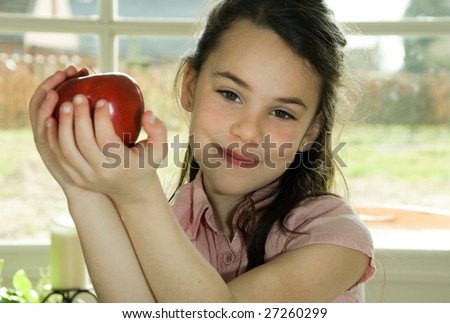 brown haired child presenting an apple. Healthy lifestyle image.