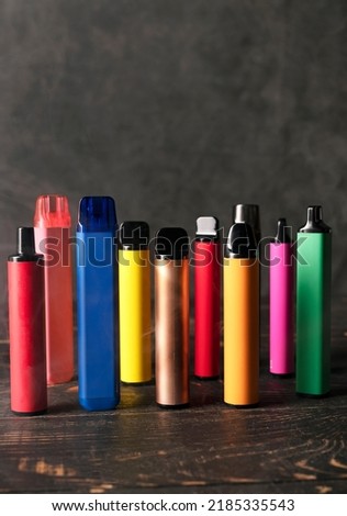 Set of colorful disposable electronic cigarettes on a dark wood background with smoke. The concept of modern smoking, vaping and nicotine. Foto stock © 