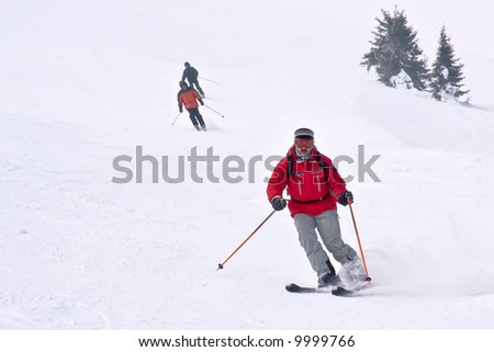 3 skiers running down from hill on European mountain resort