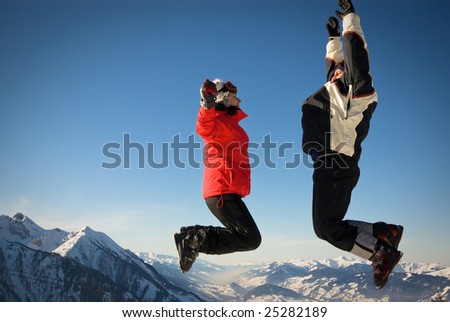 man and woman in ski cloths jumping over the snowy mountains, austria