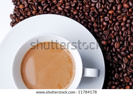 Top view of a coffee filled cup with coffee beans in the background