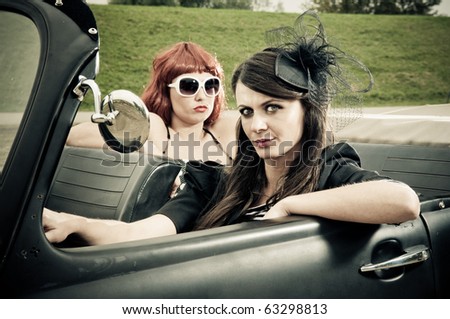 Two attractive girls driving around in vintage car