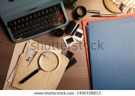 Investigator desk with confidential documents, vintage typewriter, film, magnifying glass and hat. Secret documents investigation concept. 