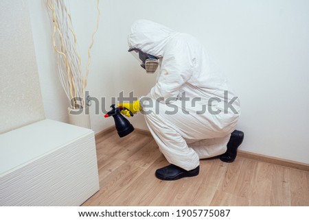 pest control worker in uniform spraying pesticides under couch in living lounge room Zdjęcia stock © 