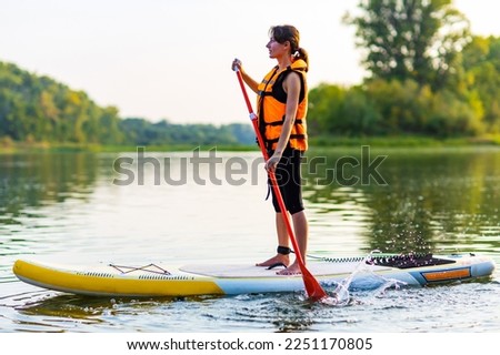 Similar – Image, Stock Photo Woman floating on paddleboard in lake