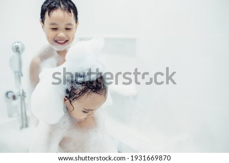 Cute little boy and girl taking bath playing with foam and soap bubbles. Hygiene for infant and baby. Soft focus. Copy space. 商業照片 © 