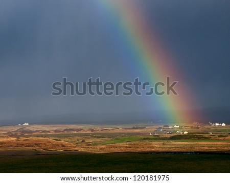 Rainbow over houses and field. Ireland.