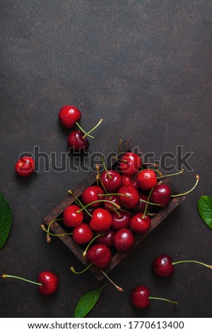 Cherry with leaf water drops on wooden box on dark brown stone table. Ripe ripe cherries. Sweet red cherries. Top view. Rustic style. Fruit Background
