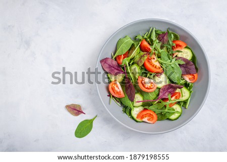 Healthy fresh salad of vegetable cucumber, tomato, spinach, arugula in plate on stone grey table. Food background for menu, recipe. Top view Imagine de stoc © 