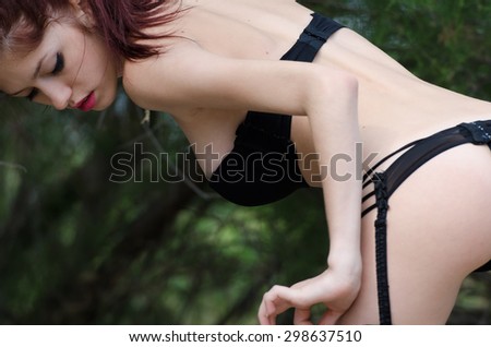 Back view of sexy young woman wearing lingerie and garter belt pose outside in nature