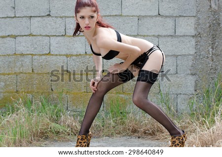Sexy young and slim woman wearing lingerie ,garter belt and tights standing outside