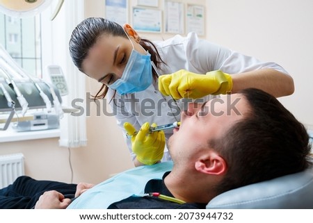 The dentist injects the patient in the gum to anesthetize the teeth. Treatment of the oral cavity. Dental care. High quality photo Сток-фото © 