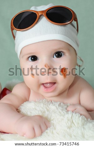 cute funny baby with sunglasses and chocolate on her face with toothless smile