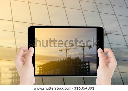 Touch screen tablet in hand on construction building background