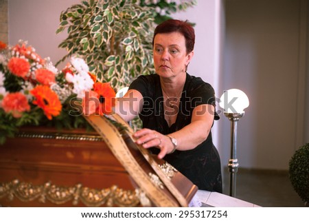 The master of funeral ceremonies prepares a coffin and flowers for burial in a ceremony hall