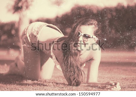 Beautiful young lady posing on the grass. Old style post-processing.