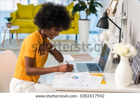 Photo of side view of smiling african american female freelancer working at home