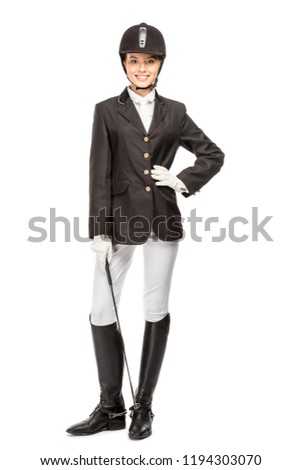 smiling young horsewoman in uniform holding horseman stick and looking at camera isolated on white Сток-фото © 