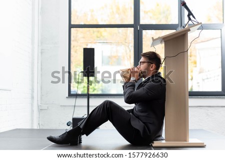side view of scared businessman in suit breathing in paper bag during conference Foto stock © 