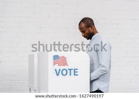 african american citizen voting near stand with vote lettering