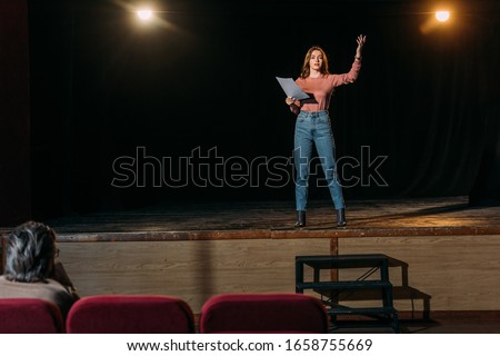 selective focus of stage director and actress reading scenario in theater