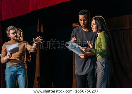 theater director, multicultural actors and actress rehearsing on stage