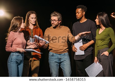 multiethnic actors and actresses rehearsing with theater director on stage