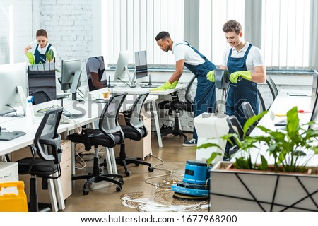 multicultural team of cleaners working in modern open space office