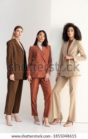 full length of interracial women in formal wear posing on white ストックフォト © 