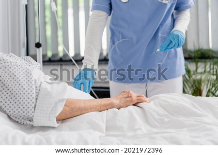 Cropped view of nurse holding catheter near senior woman on hospital bed Foto stock © 