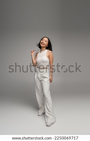 Similar – Image, Stock Photo Stylish young asian woman dressed in casual wear looking to mobile phone screen when posting photos in social media and thinking about interesting content text. Lifestyle blogger checking blog comments outdoor at autumn