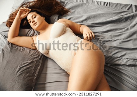 Image, Stock Photo Curvy woman in bodysuit lying on bed