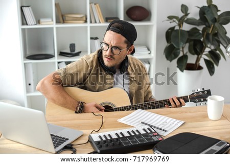 concentrated young musician playing guitar at workplace Zdjęcia stock © 