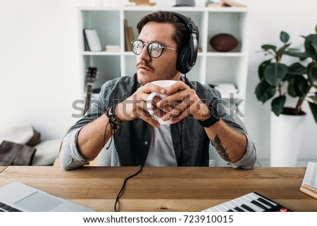 thoughtful young man listening music and drinking coffee at workplace Zdjęcia stock © 