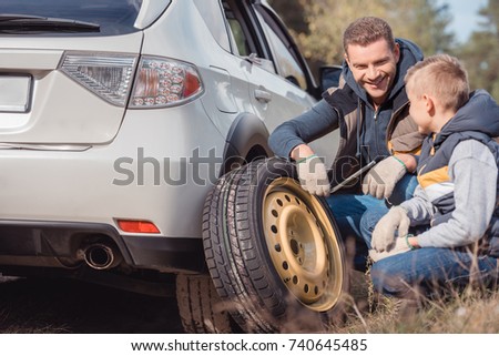 smiling father and son changing car wheel together Imagine de stoc © 