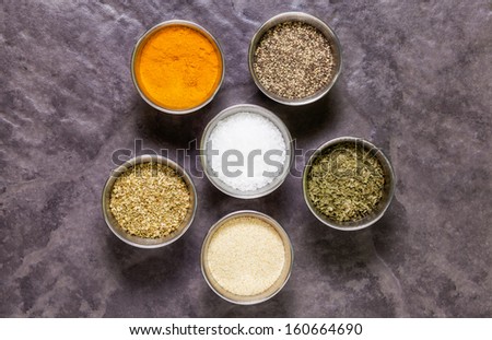 Herbs and spices in round pots on slate tile background for cooking and eating adding to meals and recipes