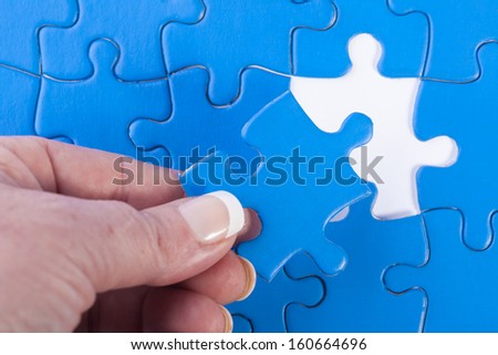 Close up of woman\'s hand placing missing piece in Jigsaw puzzle  signifying problem solving and decision making
