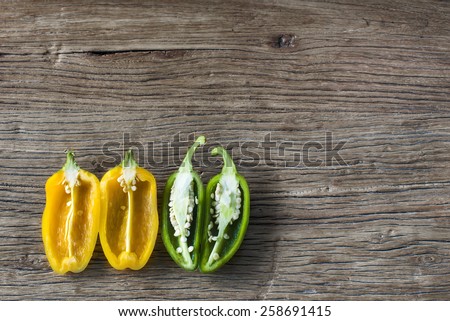 overhead view of cut yellow and green peppers in half on wooden background