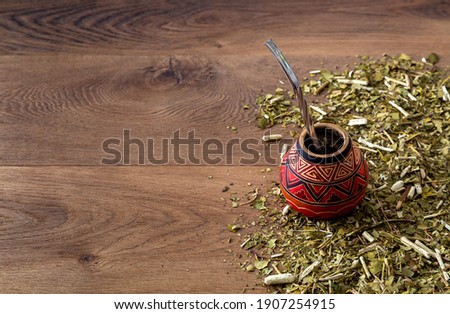 Traditional mate made of calabash over a wooden table with yerba mate scattered over it. Photo stock © 