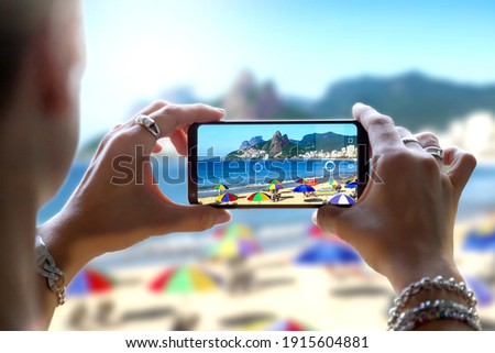 Woman in Ipanema Beach taking a photo with her mobile phone. Photographing with a camera of a smartphone in Rio de Janeiro, Brazil. Foto stock © 