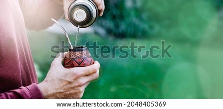 Man preparing a mate with hot water. Gourd mate with yerba inside. Middle age latin american man enjoying at the sunset outdoors. Banner format with copyspace. Photo stock © 